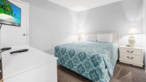 A hotel room with a bed, bedside tables, a TV, and a desk.