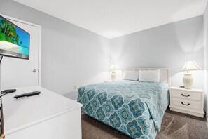 A hotel room with a bed, bedside tables, a TV, and a desk. - Oceanfront Summit Bliss 3 BR w/ balcony (North Myrtle Beach)