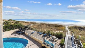 A pool area with a view of the beach and ocean.
