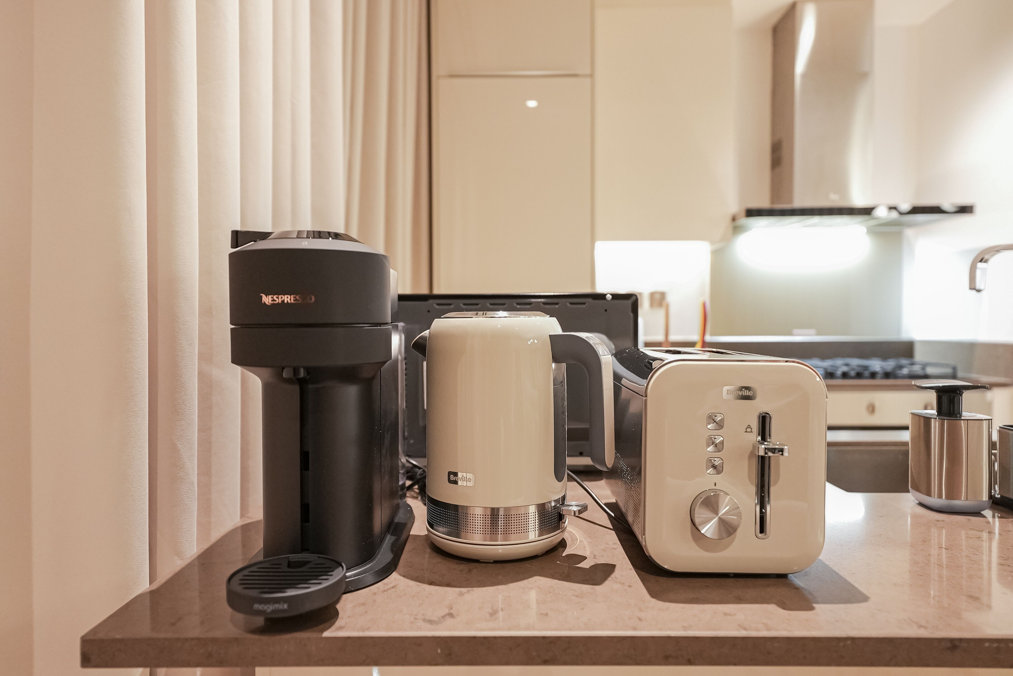 Een kitchenette met een koffiezetapparaat, een waterkoker en een broodrooster.