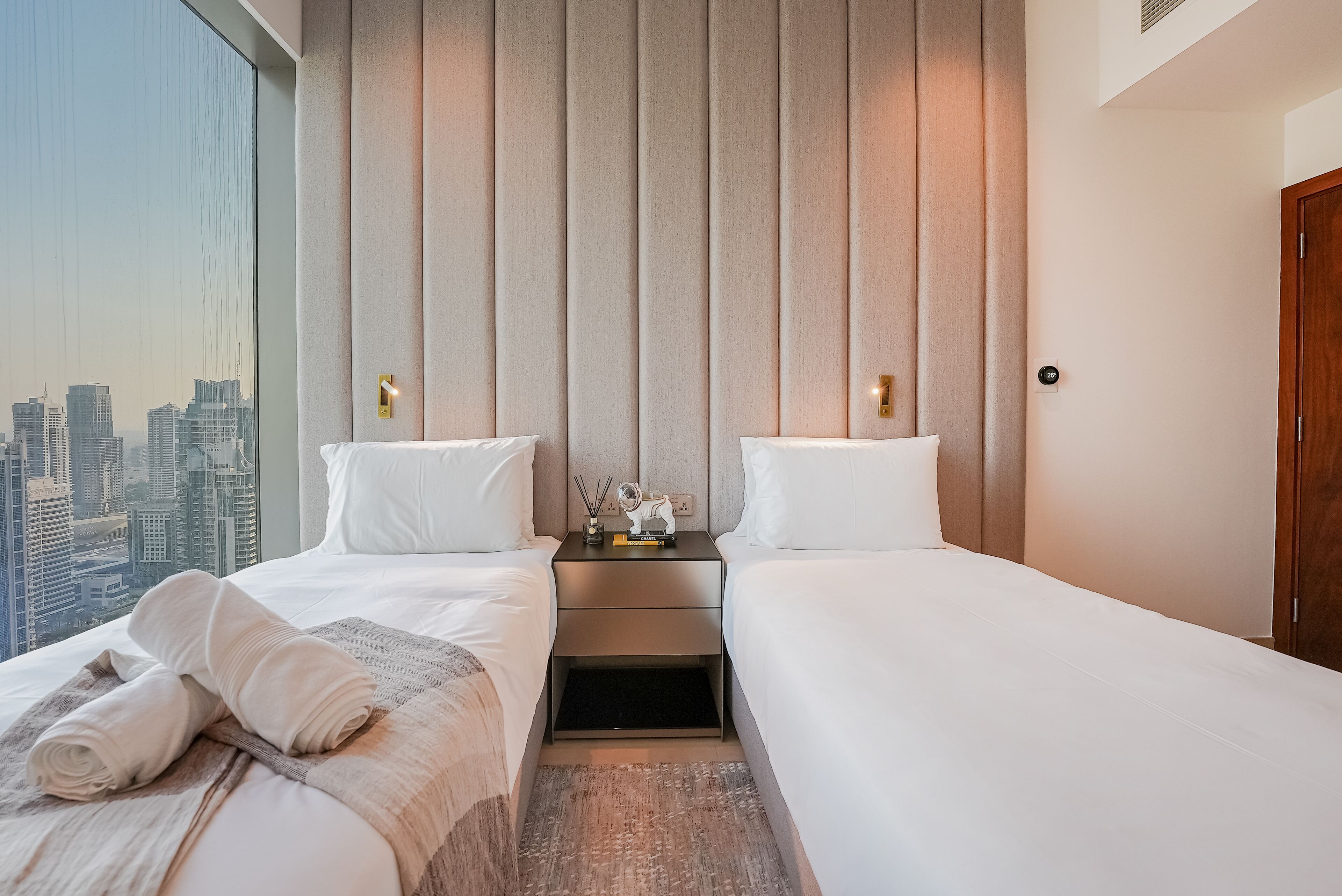Ein Hotelzimmer mit zwei Betten, einem Nachttisch und Blick auf die Stadt.