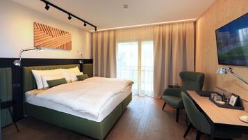 Une chambre d’hôtel moderne équipée d’un grand lit, d’un bureau, d’une chaise et d’un téléviseur.