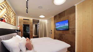 A modern hotel room with a large bed, a TV on the wall, and a wooden accent wall. - Hotel Steiermarkhof (Graz)