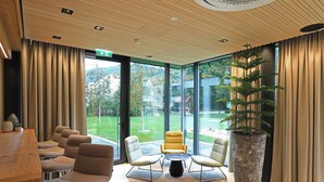 A modern interior with a wooden ceiling, large windows, and a seating area with chairs and a table. - Hotel Steiermarkhof (Graz)