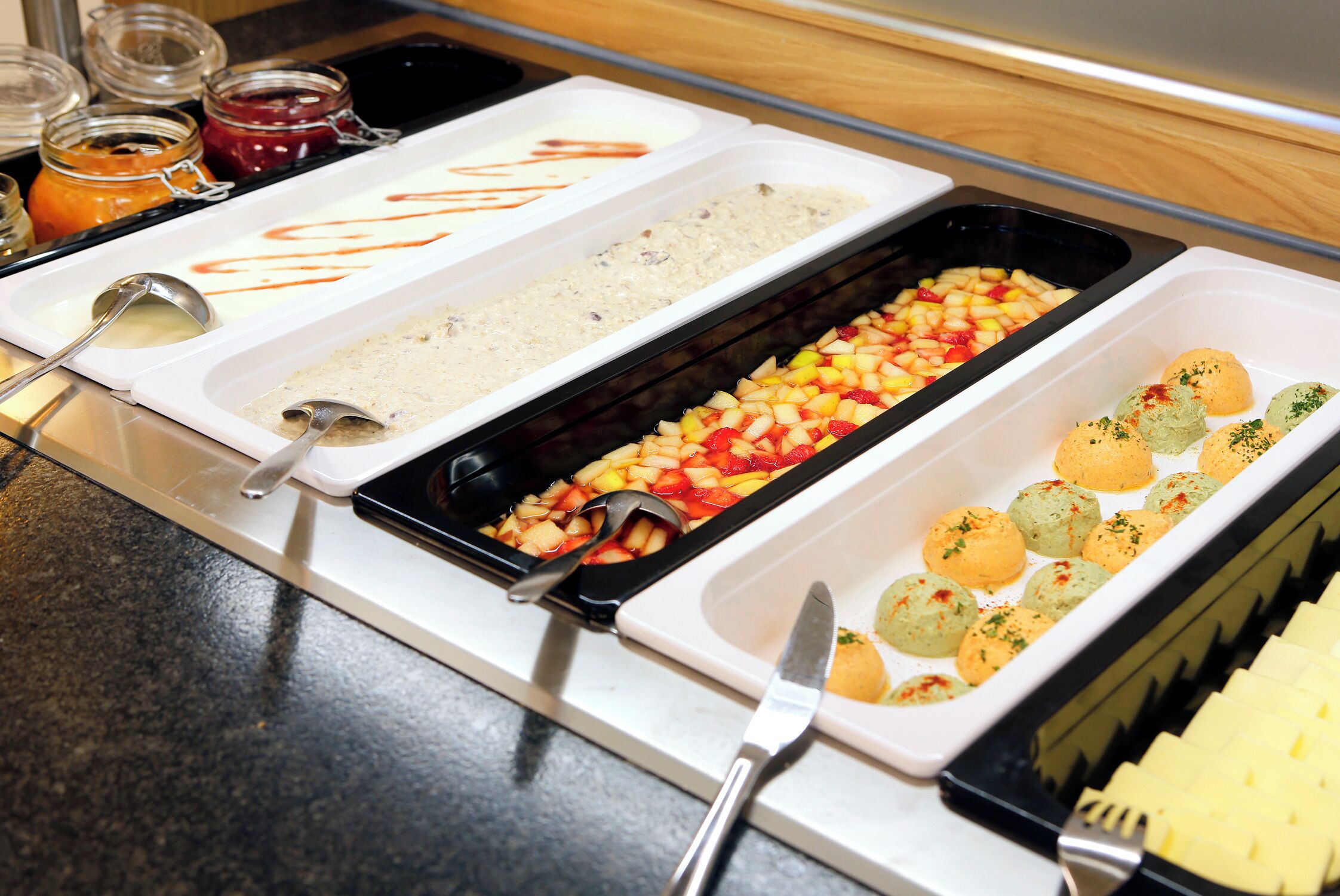Un buffet con diversi cibi, tra cui frutta, un dessert e un piatto con salsa.
