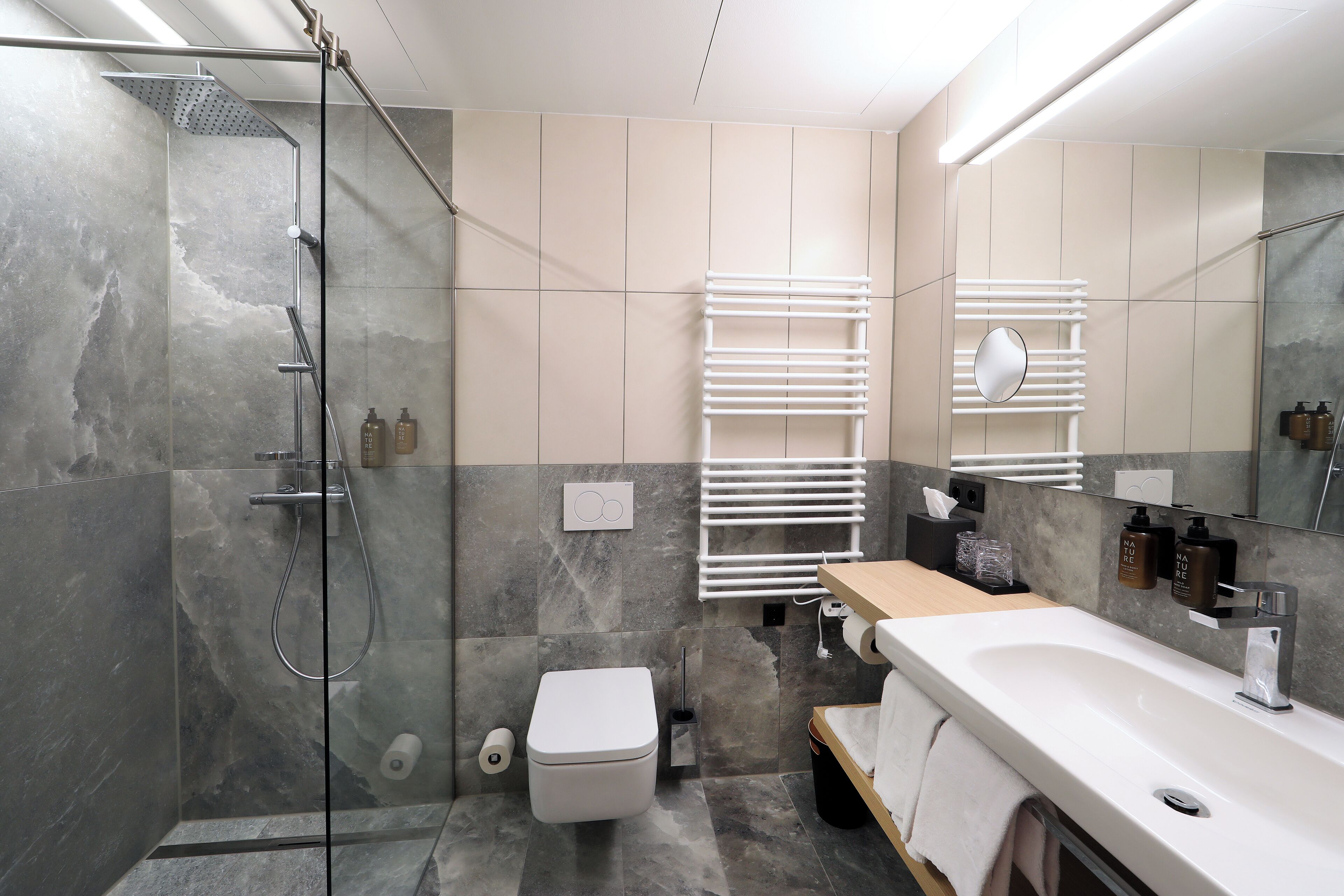 A modern bathroom with a glass-enclosed shower, a white toilet, a sink with a mirror, and a towel rack.
