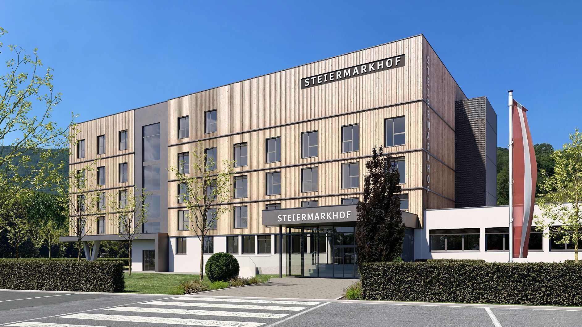Un bâtiment moderne dont la façade porte l’inscription « STEIERMARKHOF », caractérisé par une conception symétrique, de nombreuses fenêtres et une entrée centrale.