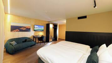 A hotel room with a bed, a sofa, a desk, and a TV.