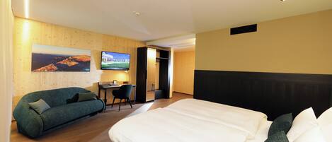 A hotel room with a bed, a sofa, a desk, and a TV.
