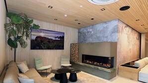 A modern living room with a fireplace, comfortable seating, and a large wall-mounted TV. - Hotel Steiermarkhof (Graz)