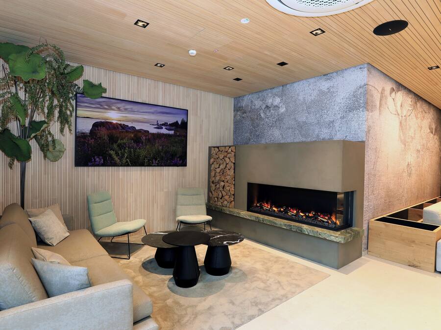 Een moderne woonkamer met een open haard, comfortabele zithoek en een grote wandgemonteerde televisie.