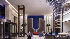 Eine moderne Lobby mit einer Rezeption, einer Sitzecke und einer großen dekorativen Leuchte.