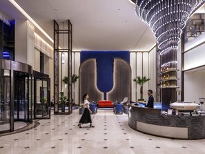 Eine moderne Lobby mit einer Rezeption, einer Sitzecke und einer großen dekorativen Leuchte.
