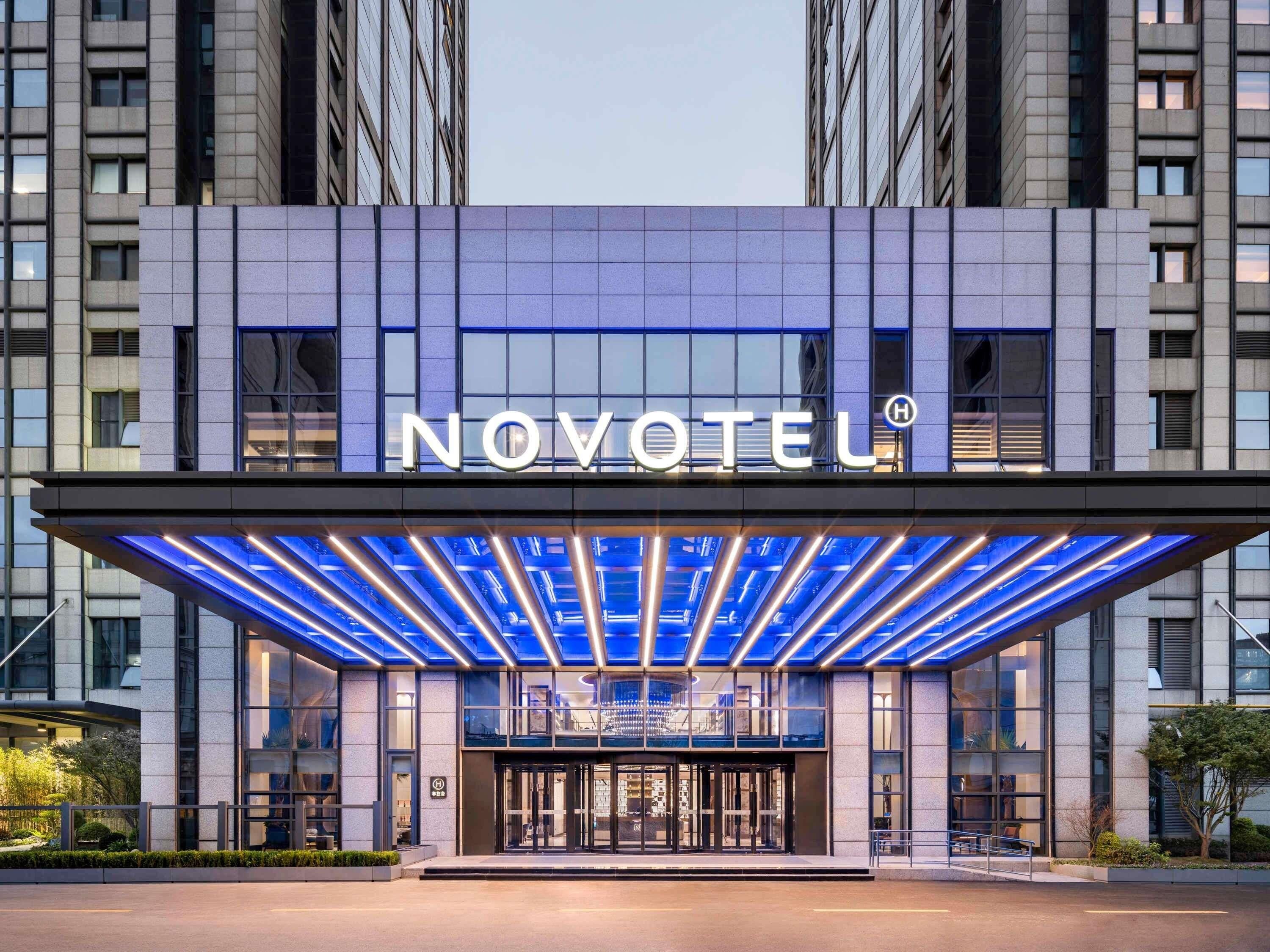 A hotel entrance with a modern design, a prominent sign, and a glass canopy.