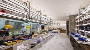 A modern buffet setup with multiple food stations, glassware, and a chef preparing food. - Novotel Shanghai Jingan (Shanghai)