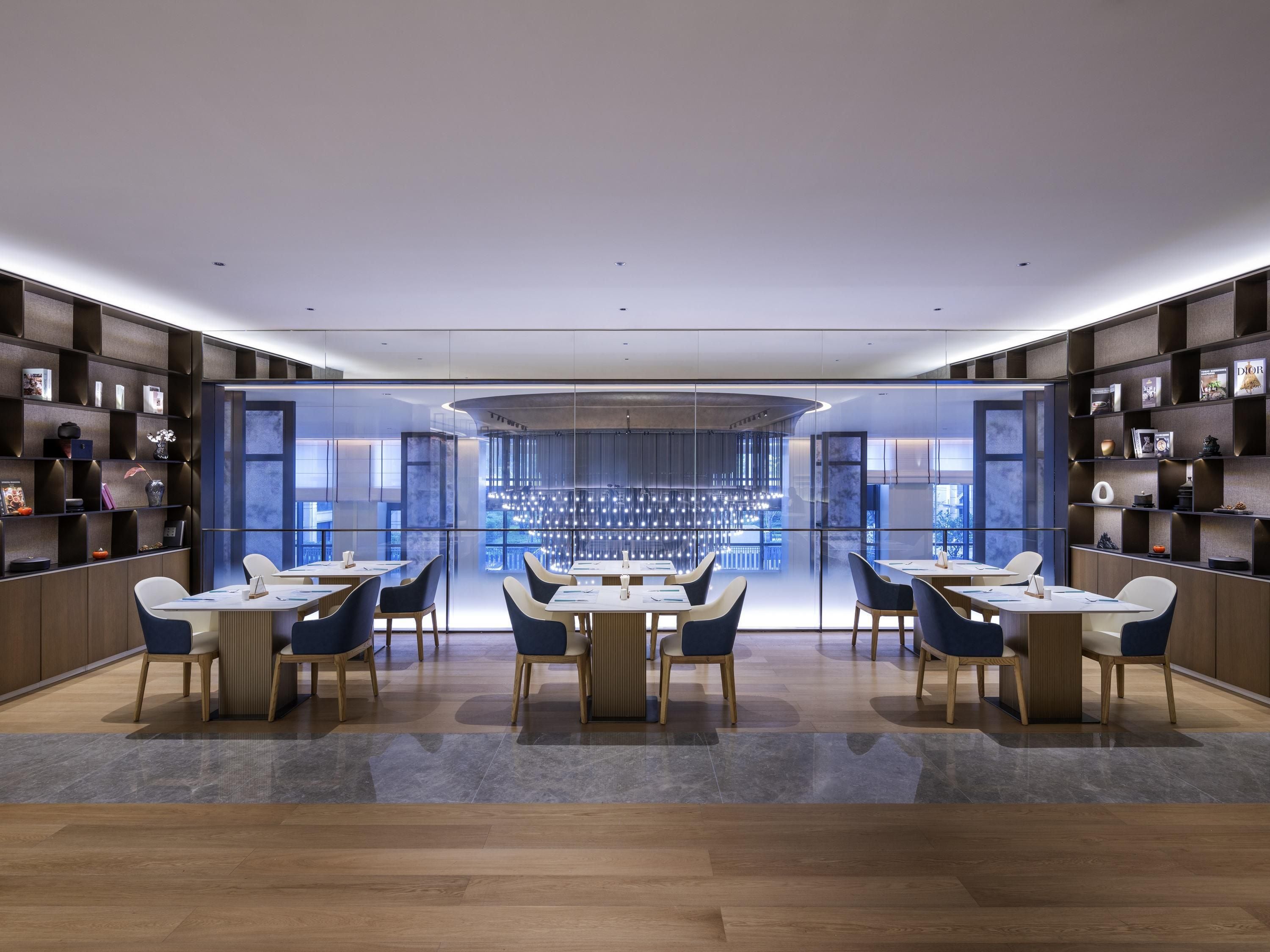 Un área de comedor moderna con una barra central, piso de madera y divisiones de vidrio.