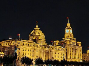 A large, historic building with a prominent dome and clock tower, illuminated at night. - Novotel Shanghai Jingan (Shanghai)