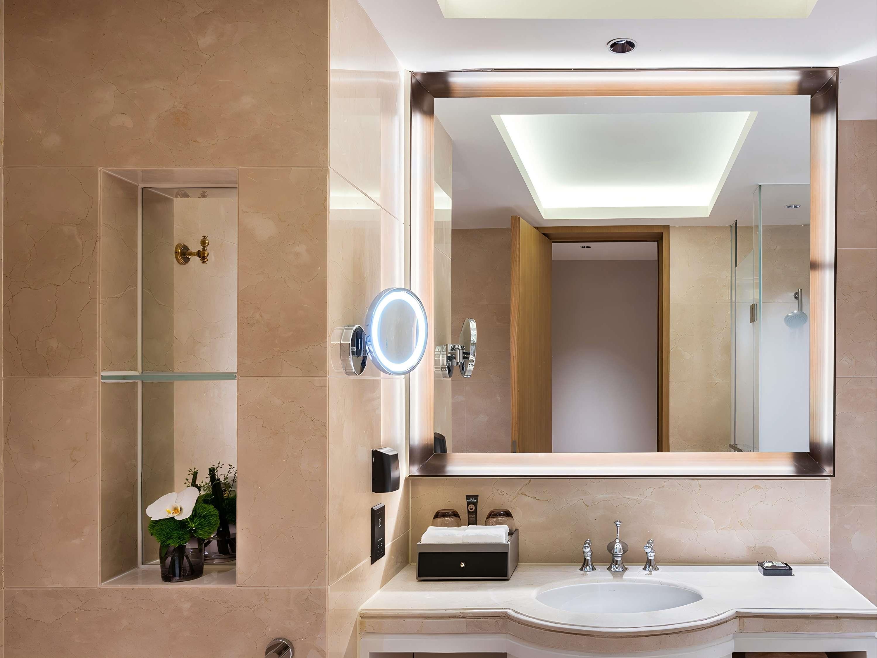 A modern bathroom with a large mirror, a glass shower enclosure, and a vanity with a sink and mirror.