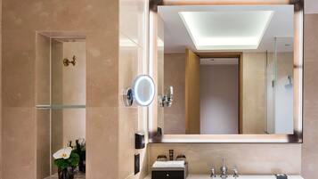 Un baño moderno con un espejo grande, cabina de ducha de vidrio y tocador con lavamanos y espejo.