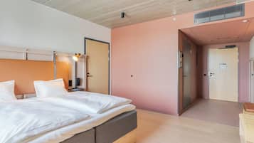 Et moderne hotelværelse med en stor seng, et garderobeskab og et badeværelse, der kan ses gennem en åben dør.
