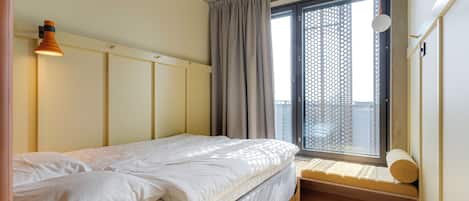 Un dormitorio con cama, una ventana con vistas, una mesita de noche y una lámpara colgante.