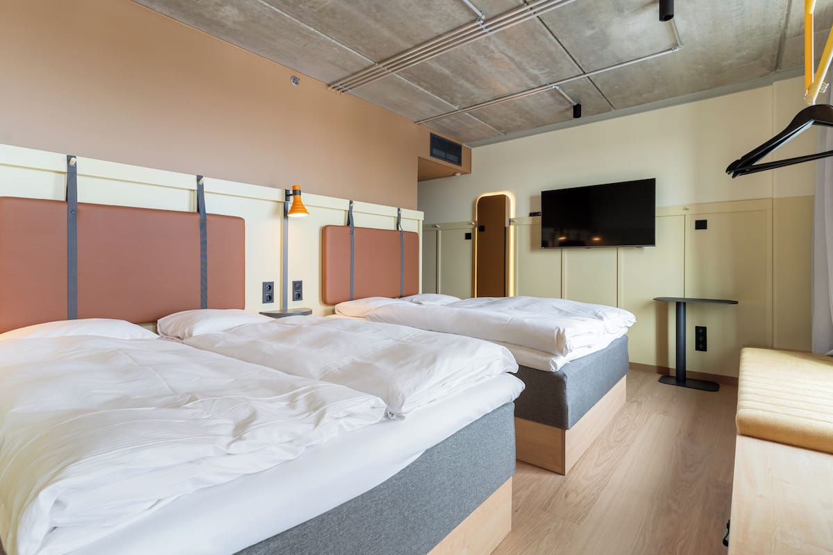 Habitación de hotel con dos camas, un televisor y una pequeña mesa.