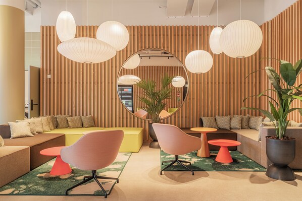 Un espace de détente moderne doté d’un grand miroir rond, de murs recouverts de lambris en bois et de nombreux sièges, notamment des canapés et des fauteuils.