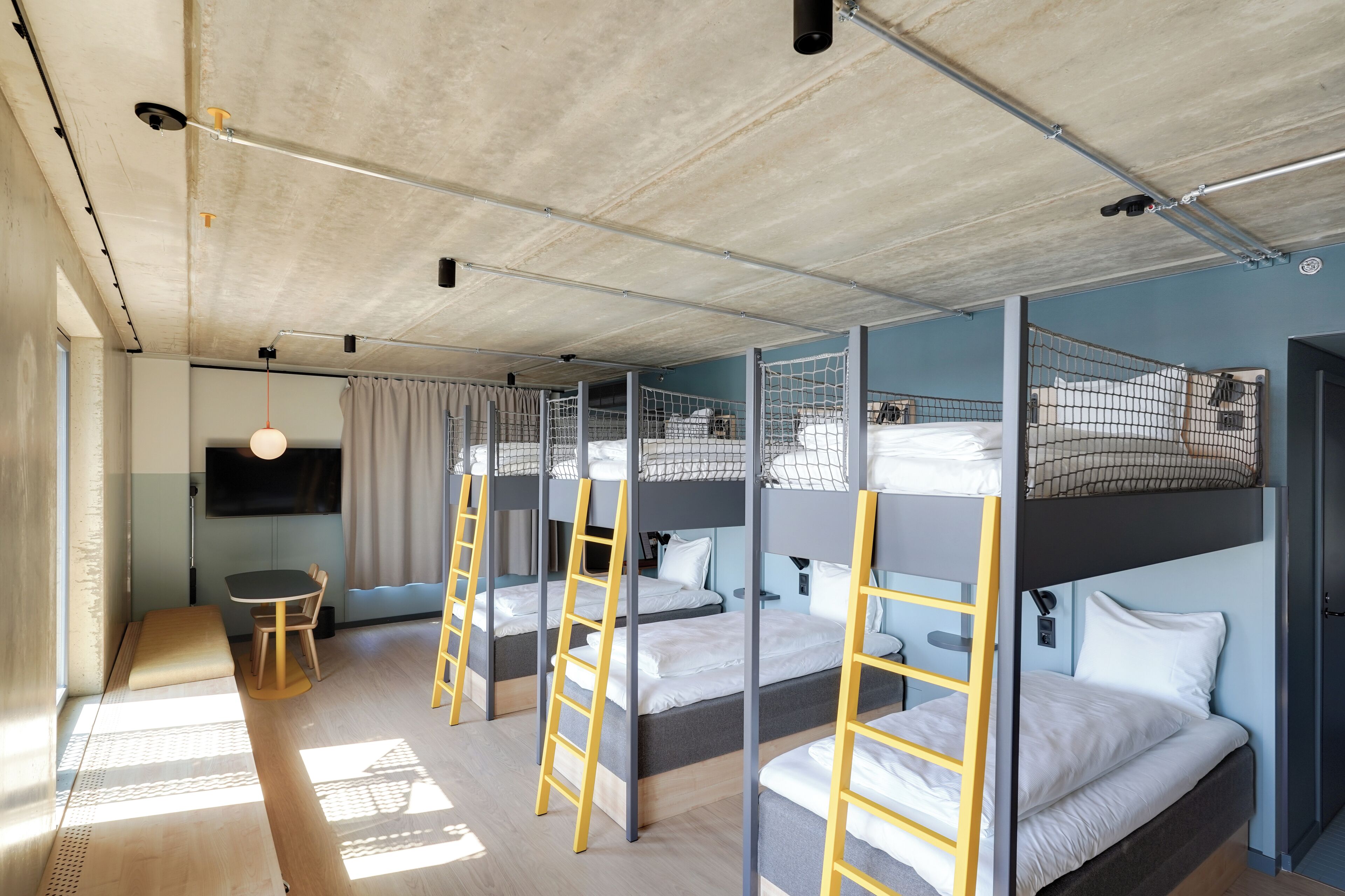 A modern hotel room with bunk beds, a desk, and a TV.
