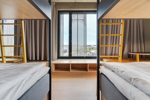 Habitación de hotel moderna con dos camas, una ventana con vistas a la ciudad y una pequeña mesa.