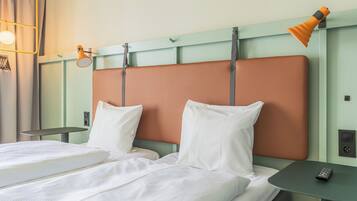 Une chambre d’hôtel avec deux lits, une petite table, une lampe et un panneau de commande fixé au mur.