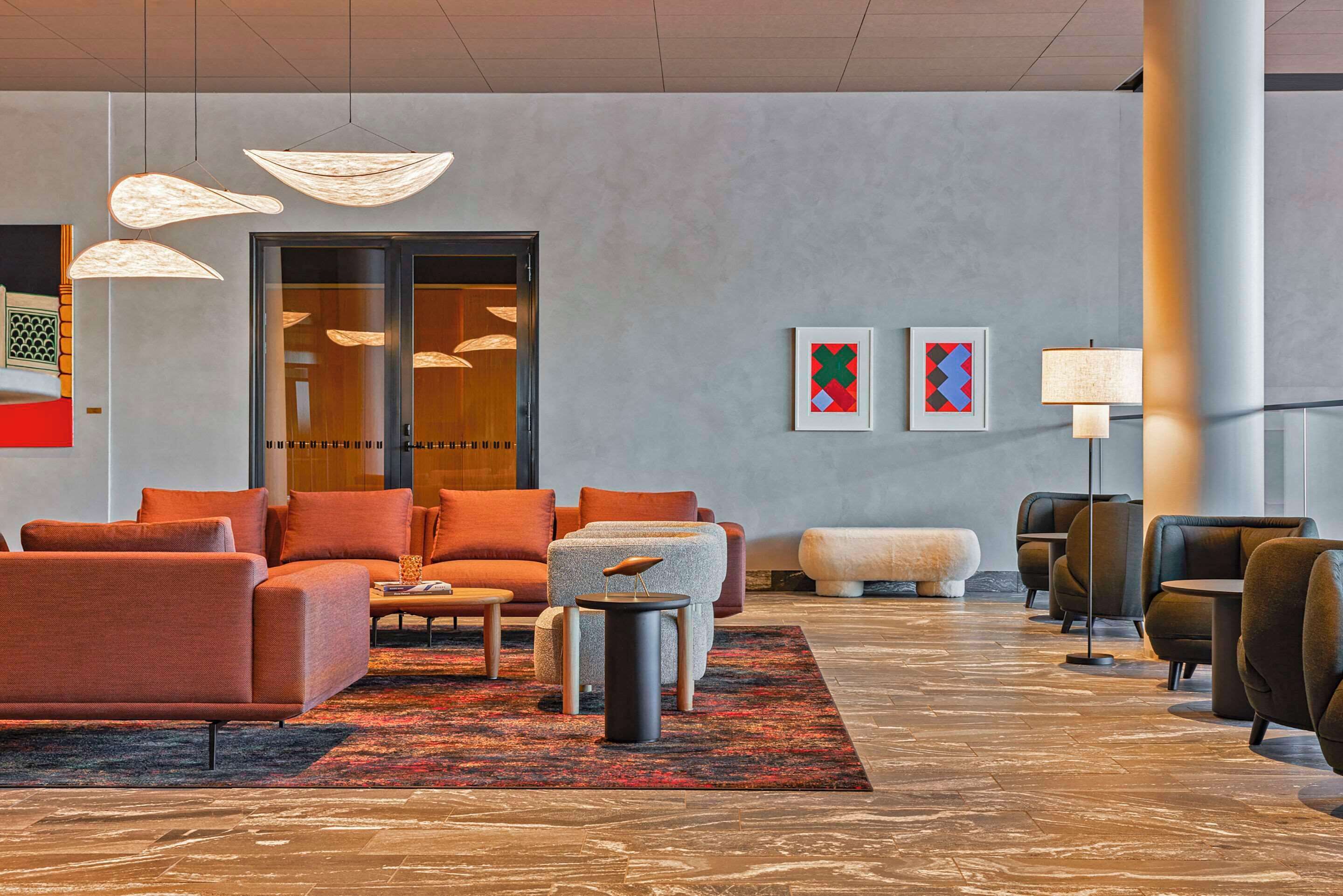 A modern lobby with seating areas, a reception desk, and artwork on the walls.