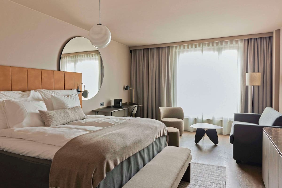 Ein modernes Hotelzimmer mit einem großen Bett, einem Schreibtisch, einem Sessel und einer Couch.