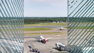 An airport runway with an airplane taxiing, airport buildings, and a clear sky.