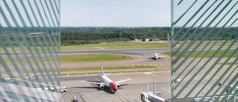An airport runway with an airplane taxiing, airport buildings, and a clear sky.