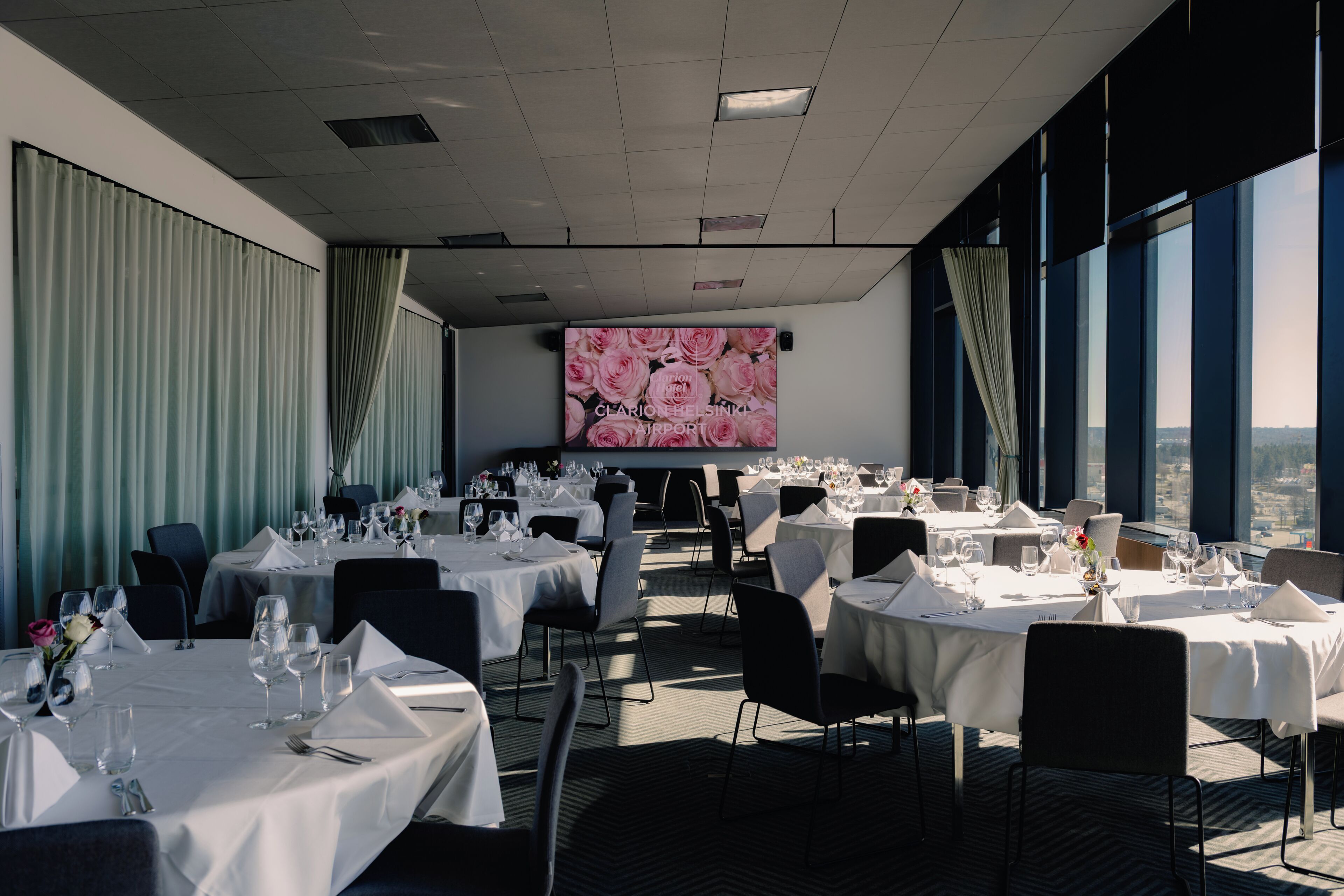 A conference room with tables set for a meeting, large windows, and a city view.