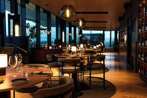 Un restaurante moderno con mesas redondas, sillas e iluminación colgante.