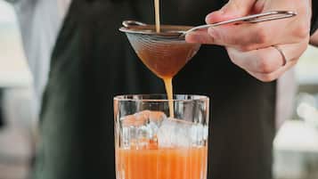 Iemand giet een drankje in een glas met ijsblokjes.