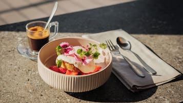 Dessert in einer Schüssel mit Löffel und einer Tasse Kaffee auf einem Tisch.