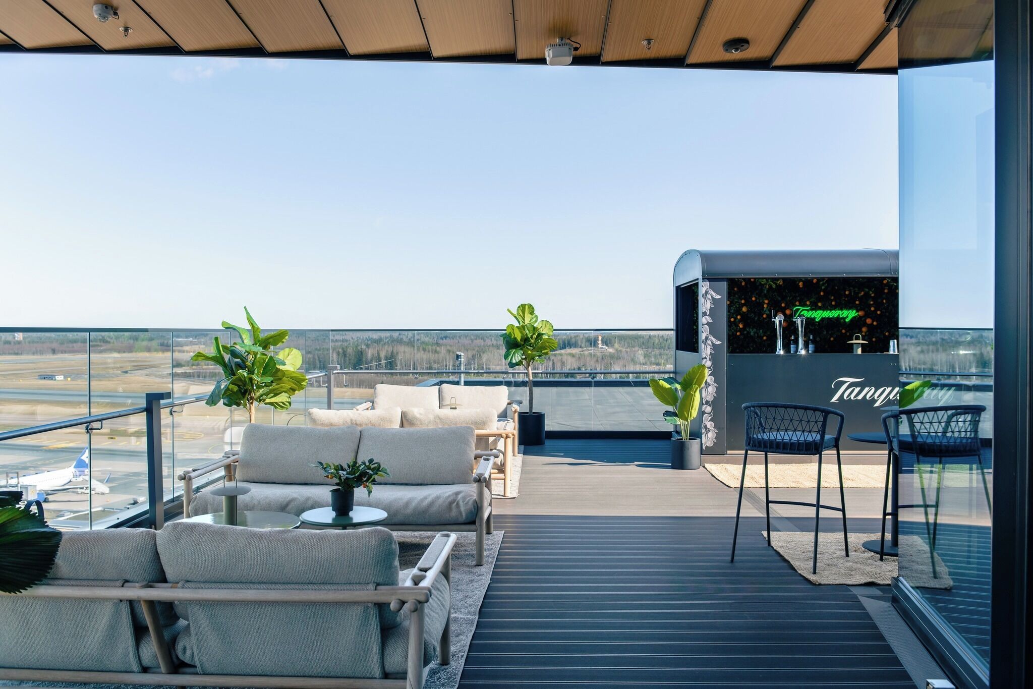 A rooftop terrace with outdoor seating, a bar area, and a view of the landscape.