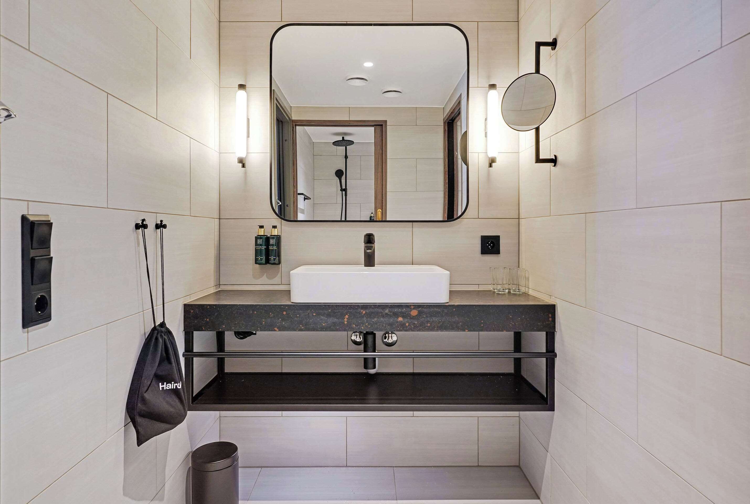 A modern bathroom with a large mirror, a sink, and a handheld showerhead.