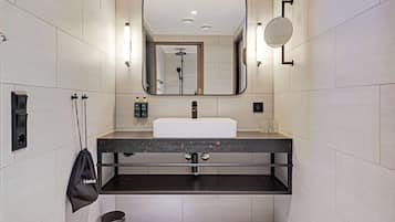 Un baño moderno con un espejo grande, un lavabo y un cabezal de ducha manual.