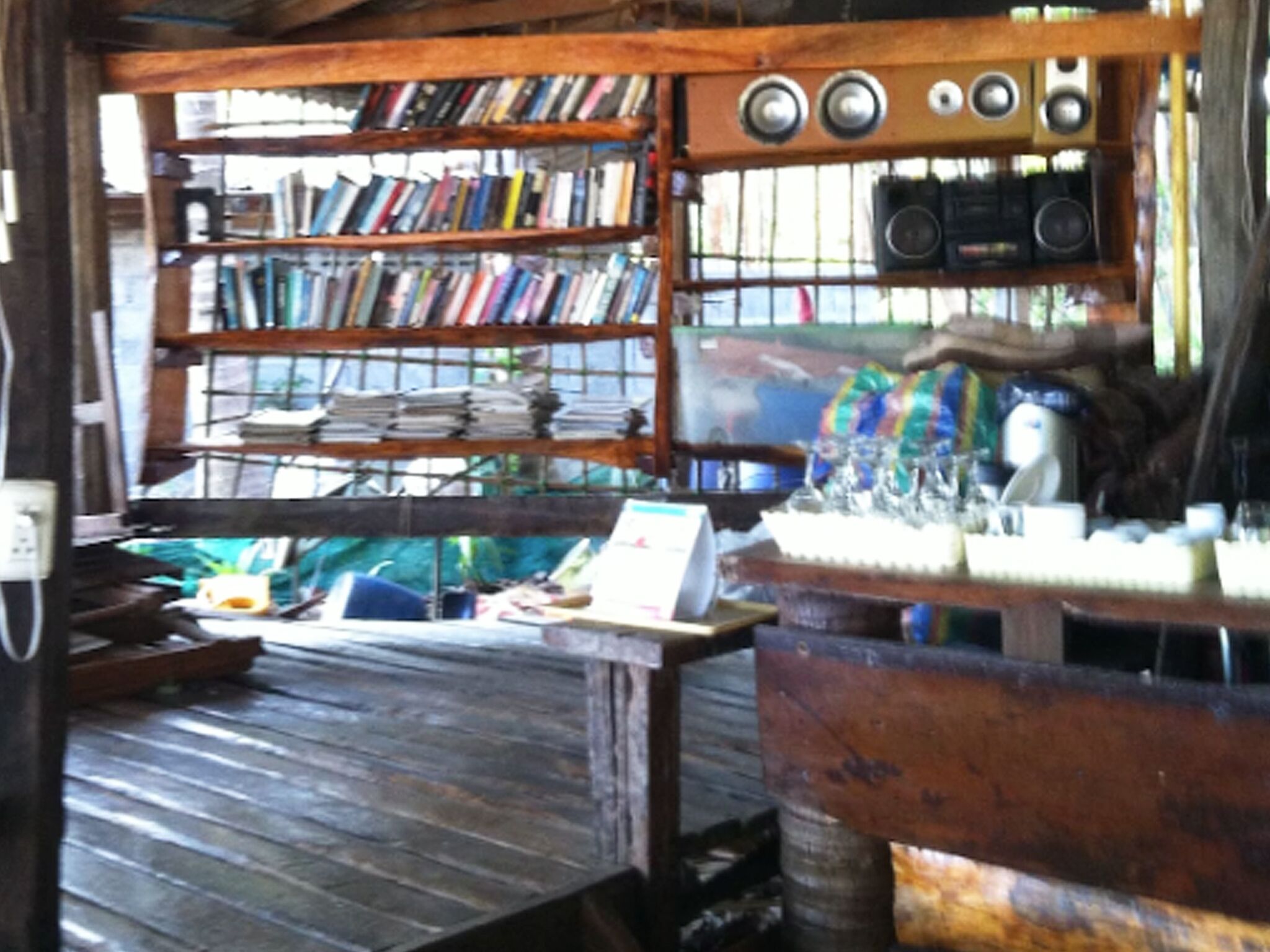 Une pièce rustique avec des étagères en bois remplies de livres, une table sur laquelle sont disposés divers objets et un système de haut-parleurs.
