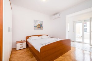 Una camera da letto con un letto di legno, un comodino, un quadro e una porta scorrevole in vetro che dà sull'esterno.