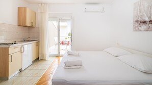 Hotellihuone, jossa on sänky, pieni keittiö ja näkymä ulos.