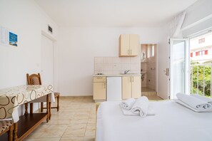 Ein kleines Hotelzimmer mit Bett, Esstisch, Küchenzeile und Bad.