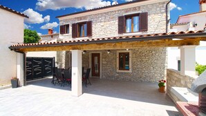 Una casa de piedra con un porche cubierto, un portón negro y una mesa con sillas.