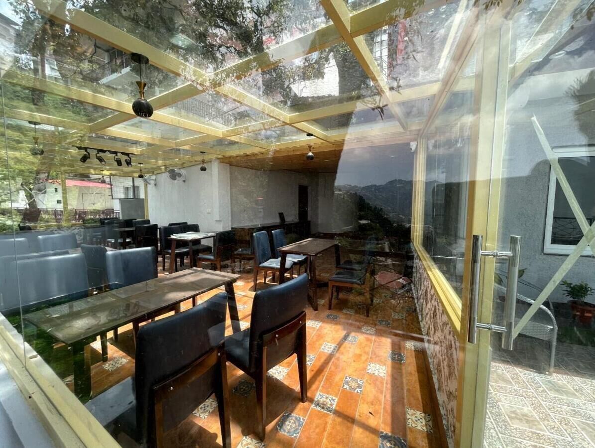 An indoor dining area with tables and chairs, a glass ceiling, and a view of the outdoors.