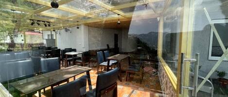 An indoor dining area with tables and chairs, a glass ceiling, and a view of the outdoors.