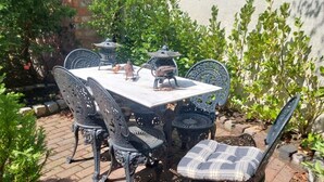 Patio esterno con tavolo e sedie, immerso nel verde e circondato da un muro di pietra.
