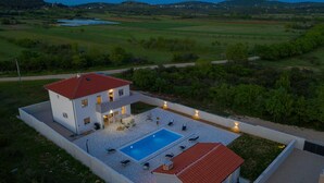 Une maison moderne dotée d’une piscine, d’un espace salon extérieur et offrant une vue sur la campagne environnante.